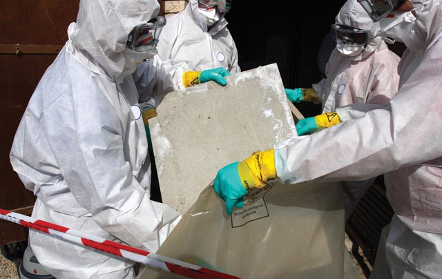 Staff removing some asbestos in a post of transformer, Reflection of mask of man opposite was created for cannot be recognized